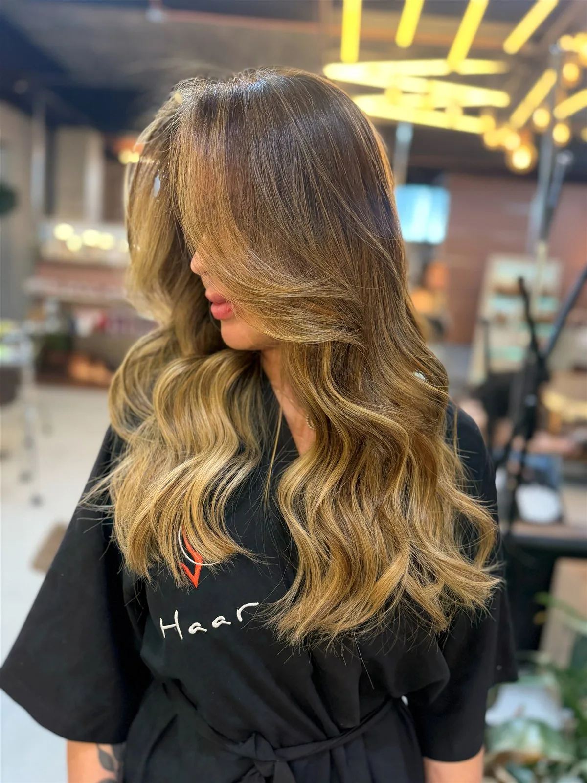 Cliente da HAAR by RUPP com balayage iluminado e ondas, vestindo o robe do salão