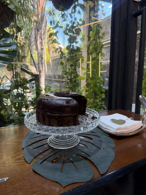 Bolo de chocolate servido no bistrô da HAAR by RUPP, com o jardim ao fundo