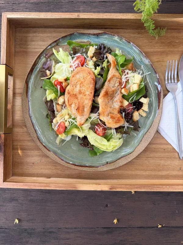 Salada com frango servida em bandeja de madeira no bistrô da HAAR by RUPP